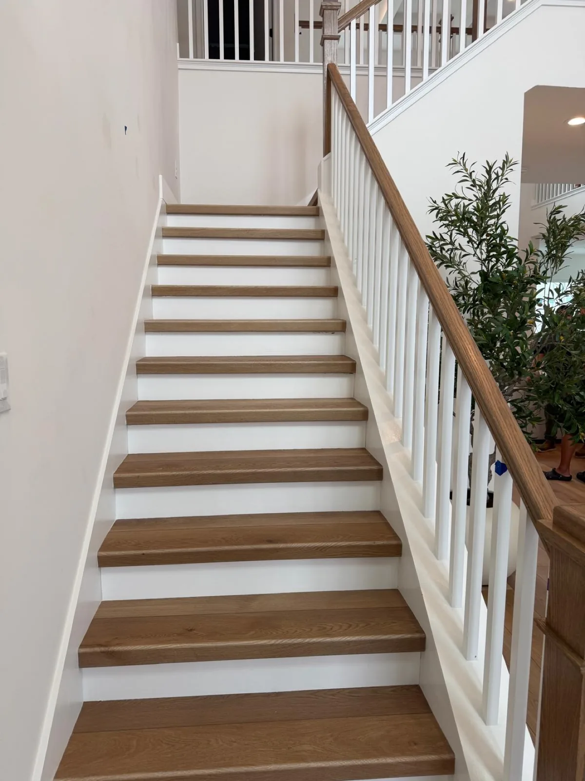 Finished wood staircase with white balusters completed by Braga Remodeling