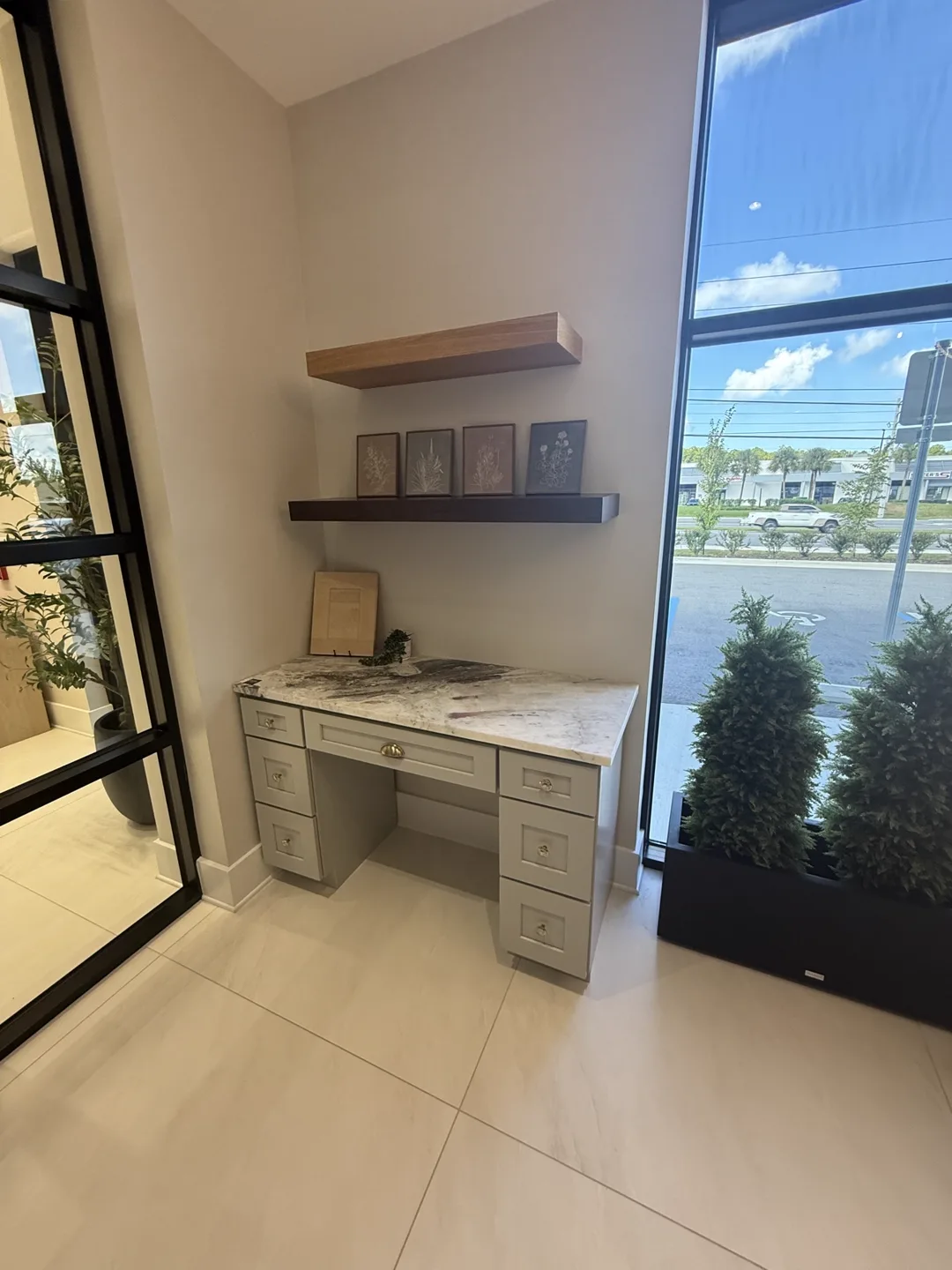 Vanity nook with floating wood shelves, framed art and marble-look top — design idea from a supplier showroom