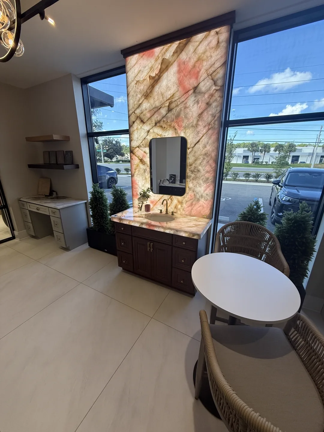 Vanity with backlit natural stone accent wall, dark wood cabinet and round mirror — design idea from a supplier showroom