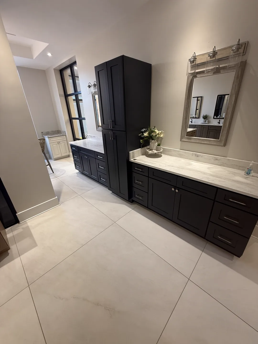 Black vanity cabinets with tall linen tower and white marble-look tops — design idea from a supplier showroom