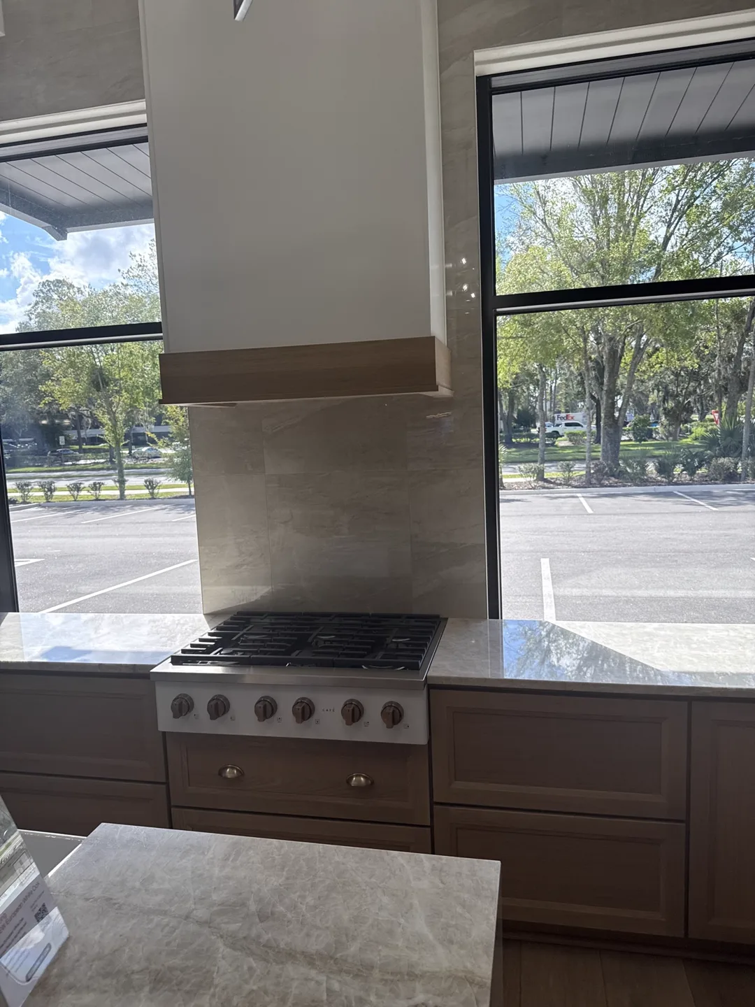 Range wall with wood hood trim, marble-look tile surround and professional gas range — design idea from a supplier showroom