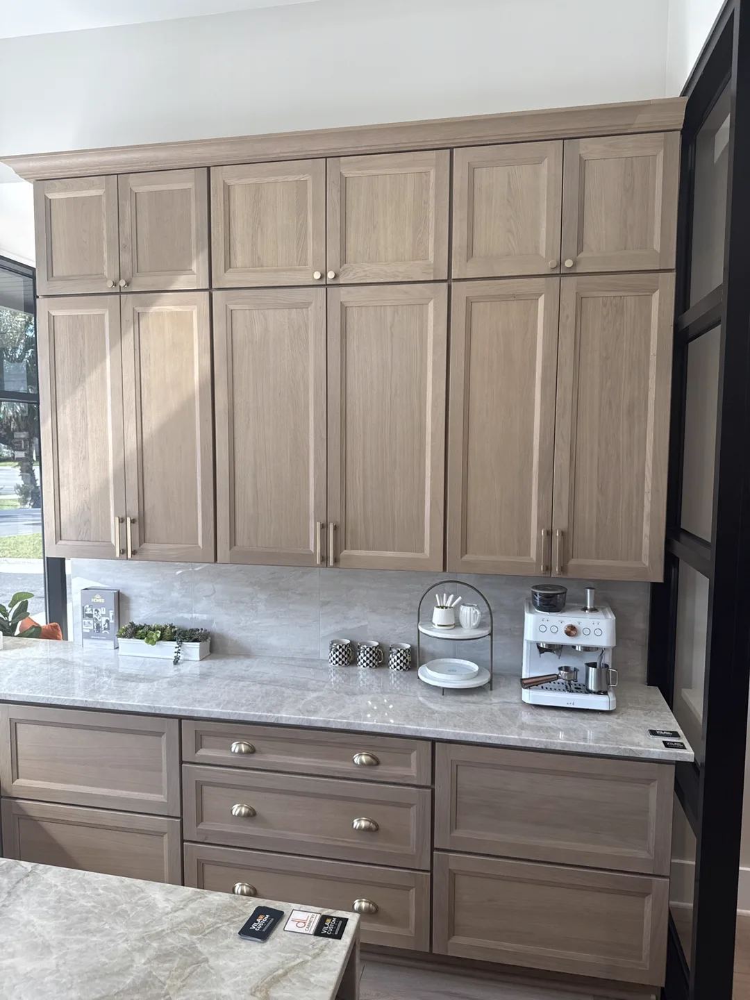 Light gray shaker kitchen with brick-look backsplash, quartz counters and stainless range — design idea from a supplier showroom