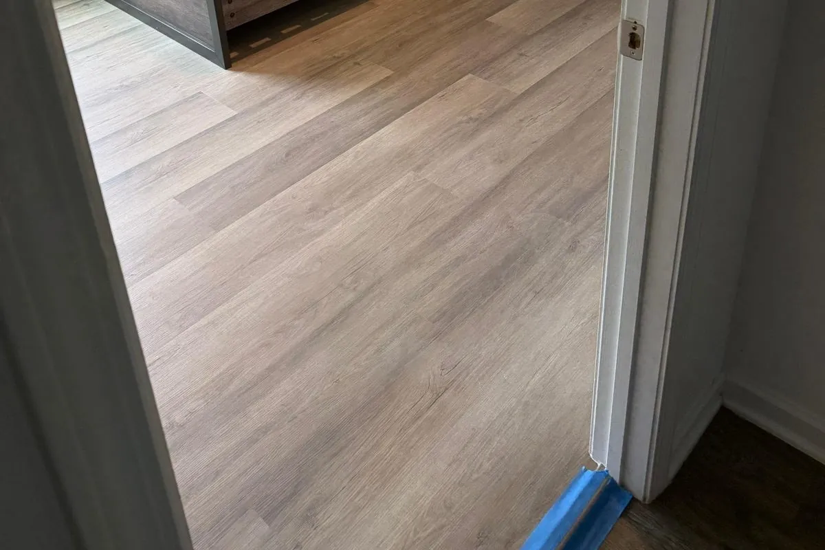 Warm-toned vinyl plank flooring in a bedroom installed by Braga Remodeling